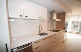 Bright kitchen with white cabinets, granite countertops, and hardwood floors.