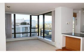 Bright kitchen with modern stainless steel appliances, black countertops, and a city view.