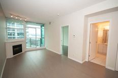 Spacious living room with hardwood floors, large windows offering city views, and a cozy fireplace.