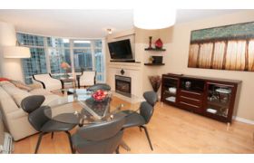 Furnished 1-bedroom + den condo with hardwood floors, city view, and modern decor.