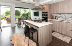 Modern kitchen with white countertops and black bar stools, showcasing a cozy living space and city view.