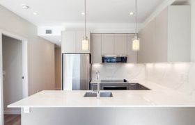 Bright kitchen with sleek white countertops and light wood flooring.