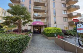 Furnished 1-bedroom condo with a cozy entrance, vibrant greenery, and a pink awning.