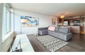 Living room with gray sectional sofa and abstract wall art on dark hardwood floors.