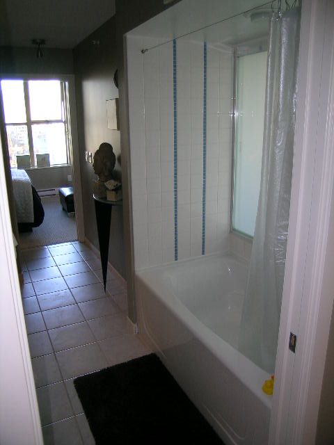 Bright bathroom with tiled floor and bathtub, city view from window. - 703 - 1000 Beach Avenue, Vancouver Downtown