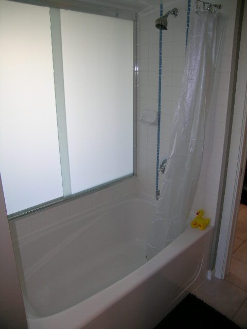 Bathroom with bathtub, frosted glass shower door, and white tile walls. - 703 - 1000 Beach Avenue, Vancouver Downtown