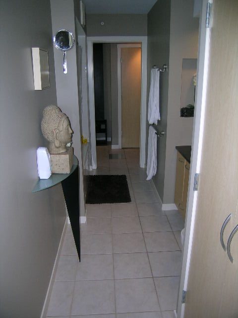 Bright hallway leading to bathroom with white towels and a Buddha statue on the wall. - 703 - 1000 Beach Avenue, Vancouver Downtown