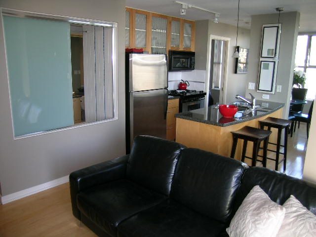 Bright living room with black leather couch and hardwood floors. - 703 - 1000 Beach Avenue, Vancouver Downtown
