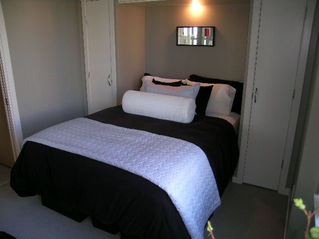 Bright bedroom with black and white bedding, modern decor, and a small mirror above the bed. - 703 - 1000 Beach Avenue, Vancouver Downtown