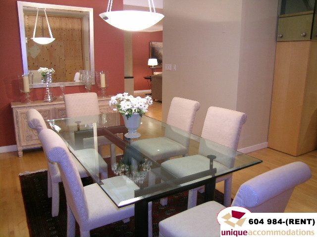 Furnished dining room with glass table, white chairs, and red accent wall. - 700 - 1888 York Ave, Vancouver West Side