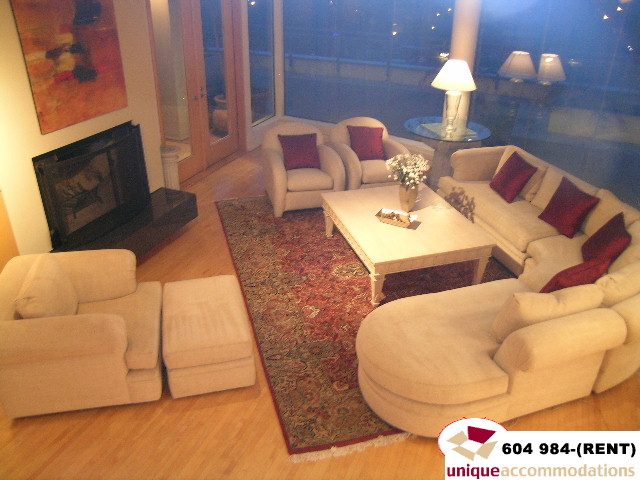 Furnished living room with hardwood floors, large windows, and a cozy fireplace. - 700 - 1888 York Ave, Vancouver West Side