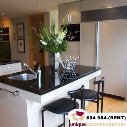 Bright kitchen with black countertops, modern bar stools, and a sleek stainless steel sink. - 700 - 1888 York Ave, Vancouver West Side