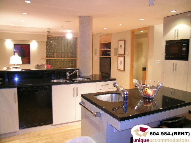 Bright kitchen with black countertops, stainless steel appliances, and hardwood floors. - 700 - 1888 York Ave, Vancouver West Side