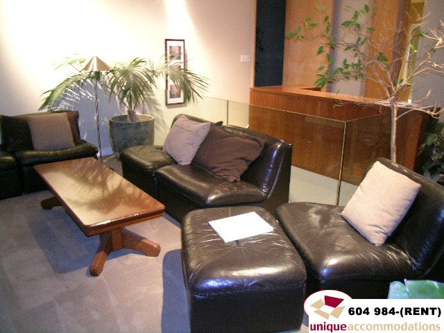 Furnished living room with leather couches, wooden coffee table, and indoor plants. - 700 - 1888 York Ave, Vancouver West Side