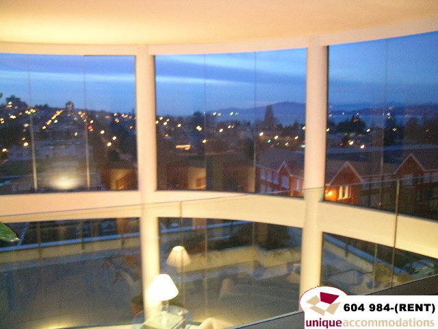 Furnished living room with large windows offering a stunning city view at dusk. - 700 - 1888 York Ave, Vancouver West Side