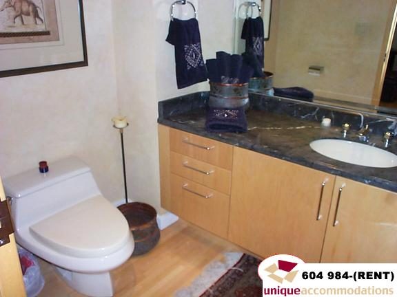 Furnished bathroom with dark granite countertops and wooden cabinets. - 700 - 1888 York Ave, Vancouver West Side