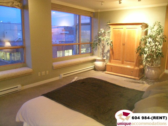 Furnished bedroom with city view and wooden furniture. - 700 - 1888 York Ave, Vancouver West Side