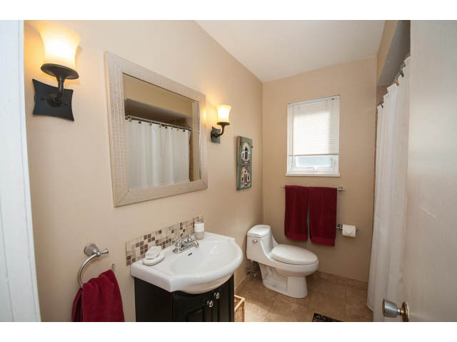 Bright bathroom with white sink, toilet, and red accents. - 1007 Shavington (Upper), North Vancouver