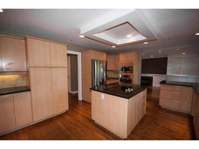 Bright kitchen with light wood cabinets, dark countertops, and hardwood floors. - 1881, Vancouver West Side