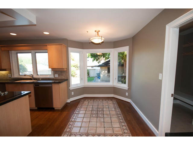 Bright kitchen with granite countertops and hardwood floors, leading to a spacious living area with a city view. - 1881, Vancouver West Side