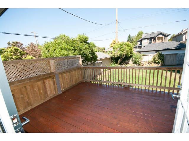 Large deck with wooden flooring and railing, surrounded by trees and houses. - 1881, Vancouver West Side