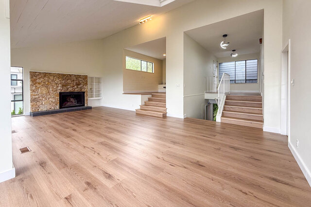 Spacious living room with light hardwood floors and a stone-clad fireplace. - 1350 Crestwell Road, West Vancouver