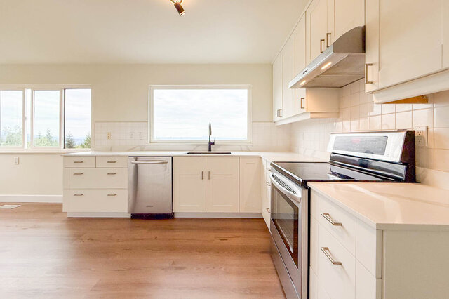 Bright kitchen with white cabinetry, stainless steel appliances, and light hardwood floors. - 1350 Crestwell Road, West Vancouver