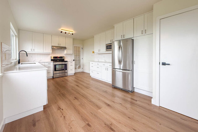 Bright kitchen with white cabinets, white countertops, stainless steel appliances, and light hardwood floors. - 1350 Crestwell Road, West Vancouver