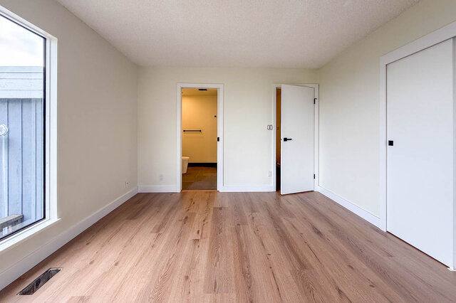 Spacious bedroom with light hardwood floors, neutral walls, and a large window letting in natural light. - 1350 Crestwell Road, West Vancouver