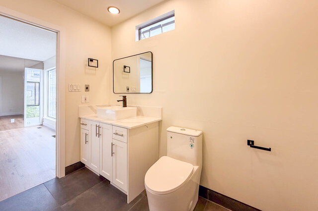 Compact bathroom with a white vanity, square vessel sink, and dark tile flooring. - 1350 Crestwell Road, West Vancouver
