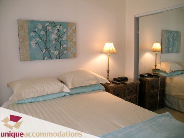 Furnished bedroom with white bedding, blue accents, and a lamp on a nightstand. - 509 - 939  Homer Street, Vancouver Downtown