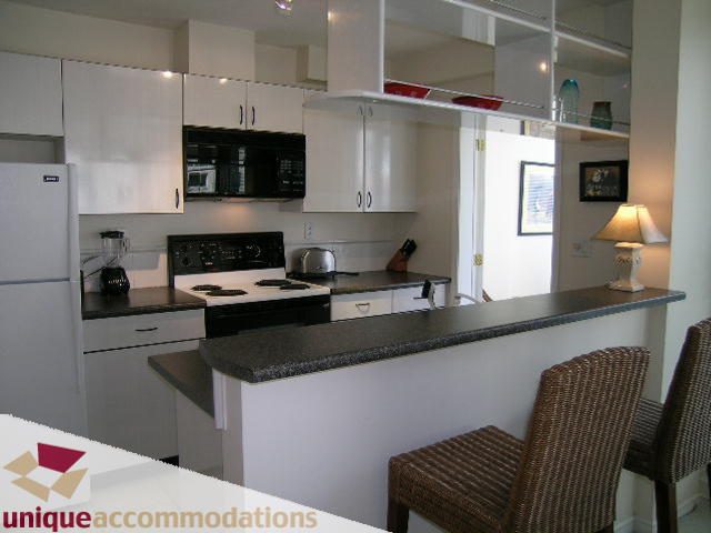 Bright kitchen with white cabinets, black appliances, and granite countertops. - 509 - 939  Homer Street, Vancouver Downtown