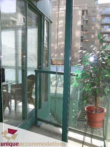 Bright living room with large glass doors, city view, and potted plants. - 509 - 939  Homer Street, Vancouver Downtown