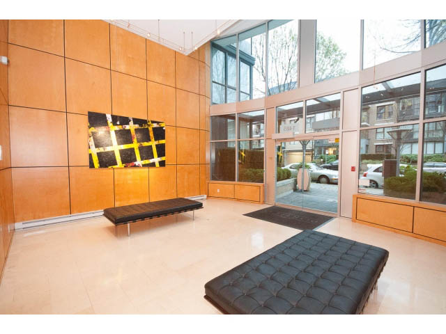 Furnished living room with modern decor, large windows offering city views, and sleek black seating. - 407 - 1485 West 6th Ave, Vancouver West Side