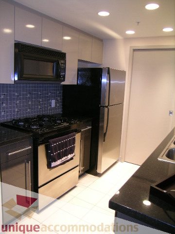 Bright kitchen with black countertops and stainless steel appliances, modern design. - 3101 - 1408 Strathmore Mews, Vancouver Downtown