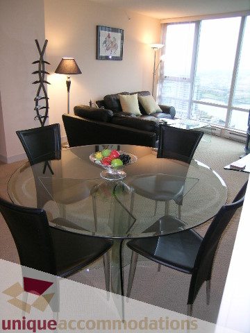 Furnished dining area with glass table, black chairs, and city view. - 3101 - 1408 Strathmore Mews, Vancouver Downtown
