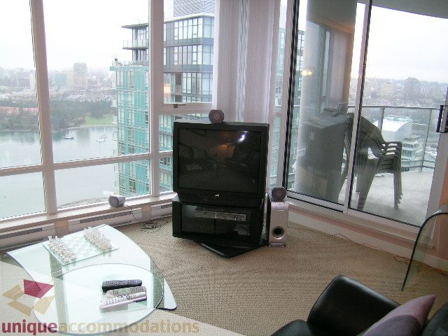 Living room with large windows, city view, modern furniture, and glass coffee table. - 3101 - 1408 Strathmore Mews, Vancouver Downtown