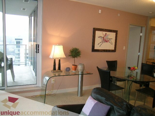 Living room with city view, modern decor, and a glass dining table. - 3101 - 1408 Strathmore Mews, Vancouver Downtown