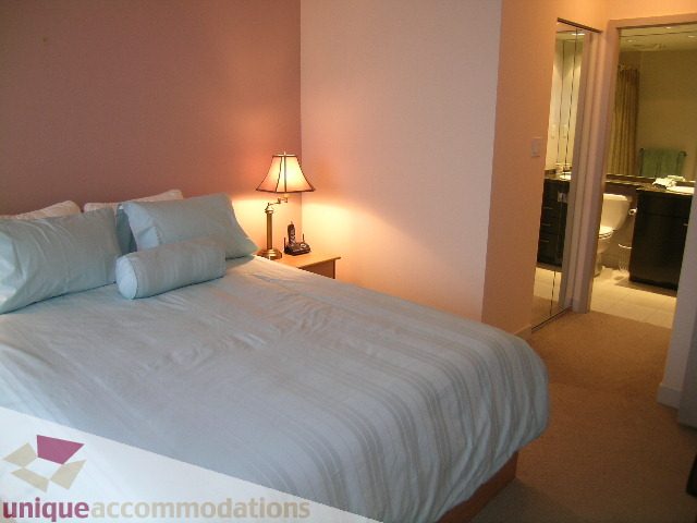 Furnished bedroom with neatly made bed, bedside table, and lamp. - 3101 - 1408 Strathmore Mews, Vancouver Downtown