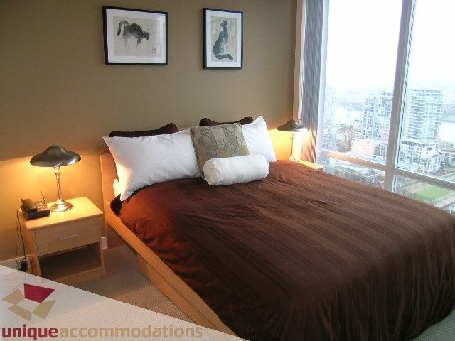 Spacious bedroom with city view, modern furnishings, and cozy bedding. - 3101 - 1408 Strathmore Mews, Vancouver Downtown