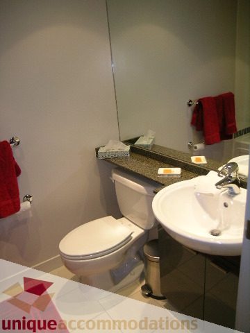 Furnished bathroom with granite countertop and red towels. - 3101 - 1408 Strathmore Mews, Vancouver Downtown