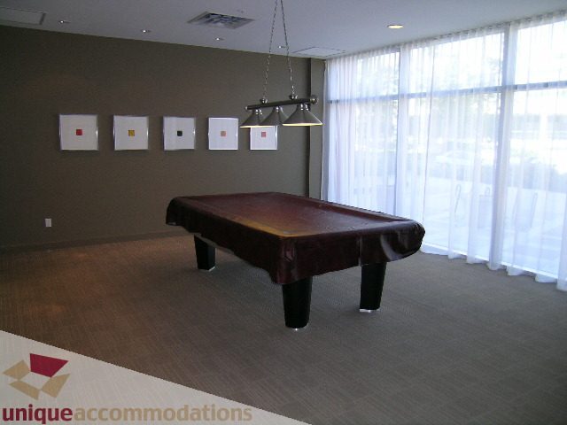 Furnished living room with hardwood floors, modern artwork, and large windows with sheer curtains. - 3101 - 1408 Strathmore Mews, Vancouver Downtown