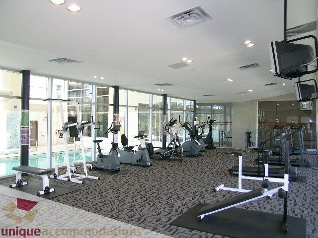 Bright fitness room with cardio machines and a city view. - 3101 - 1408 Strathmore Mews, Vancouver Downtown