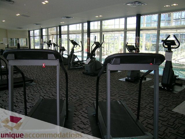 Bright fitness room with treadmills and large windows, city view. - 3101 - 1408 Strathmore Mews, Vancouver Downtown