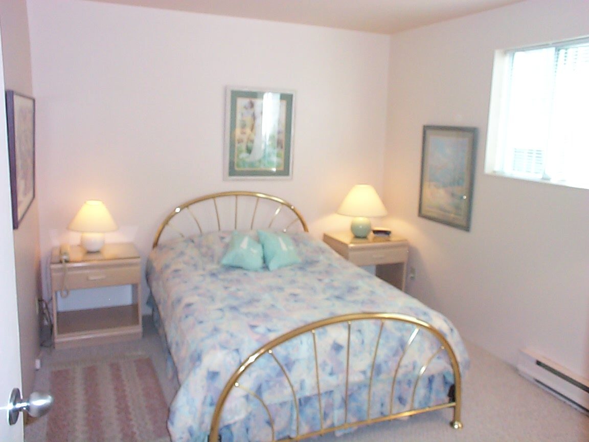 Bright bedroom with twin bed, floral bedding, and bedside lamps. - 832 West 7th Avenue, Vancouver West Side