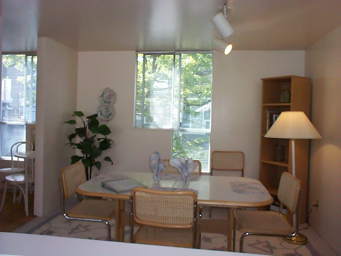 Furnished dining area with large windows, greenery, and a lamp. - 832 West 7th Avenue, Vancouver West Side