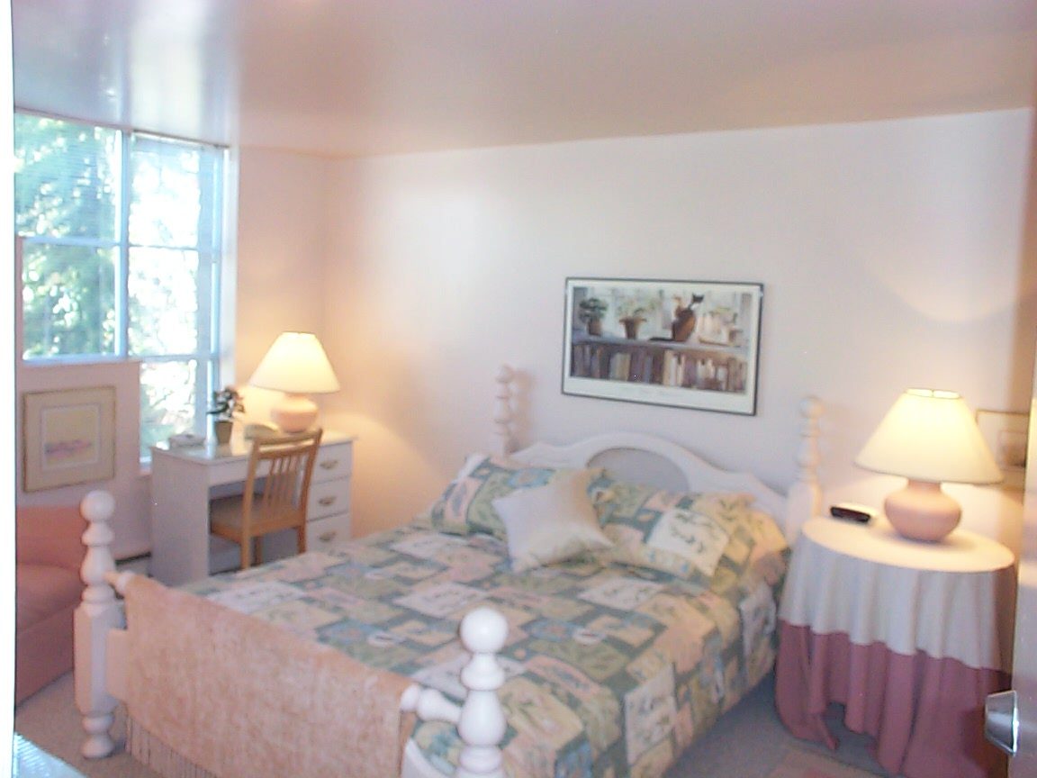 Bright bedroom with white furniture, patterned quilt, and framed artwork above the bed. - 832 West 7th Avenue, Vancouver West Side