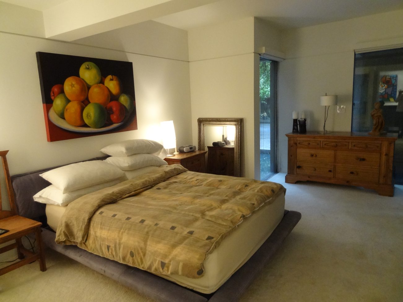 Furnished bedroom with a large bed, fruit painting, and wooden dresser. - 2898 Bellevue Avenue, West Vancouver