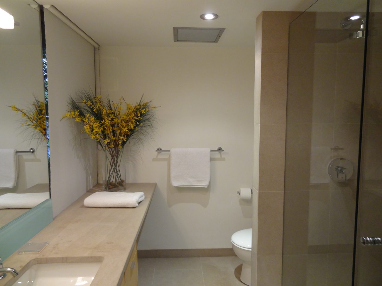 Furnished bathroom with beige countertops, modern fixtures, and a vase of yellow flowers. - 2898 Bellevue Avenue, West Vancouver