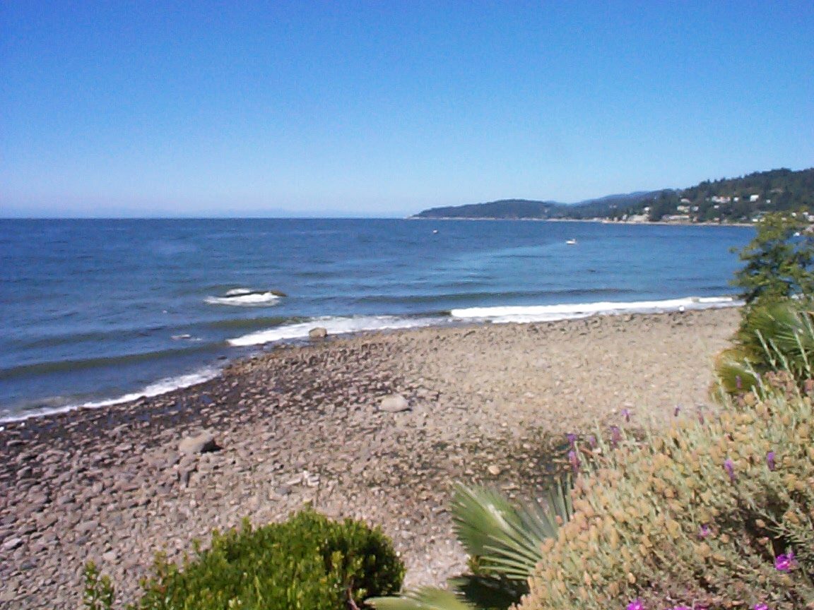 Beachfront house with pebbled shoreline and distant hills. - 2898 Bellevue Avenue, West Vancouver